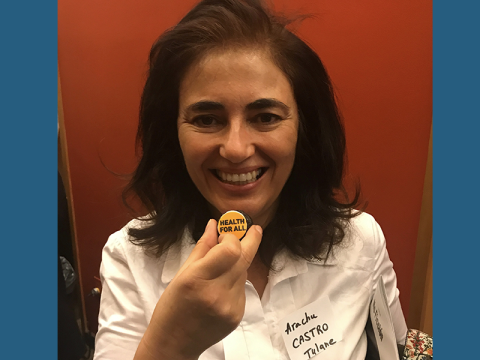 Arachu Castro, PhD, MPH, Department of International Health and Sustainable Development Arachu Castro, smiling, holding a small button that reads "Health FOr All," from the 2020 UN meeting